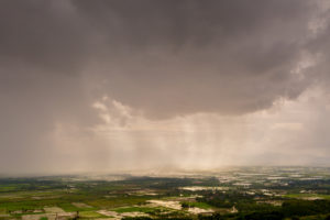 Rain curtaining a view of the mountains.Rain storm over Rice fields with curtain of rain.